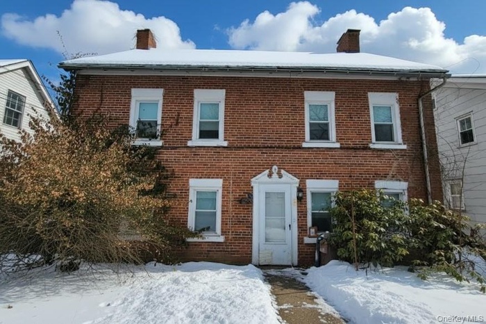 Brick Federal Colonial house featuring symmetrical chimneys. Virtually enhanced