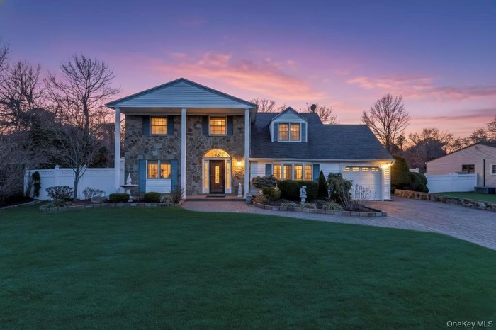 Neoclassical / greek revival house with decorative driveway, an attached garage, stone siding, and a porch