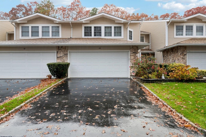 Traditional-style house featuring stone siding, asphalt driveway, and a garage