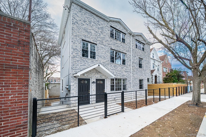 View of front facade featuring a fenced front yard, a gate, and brick siding
