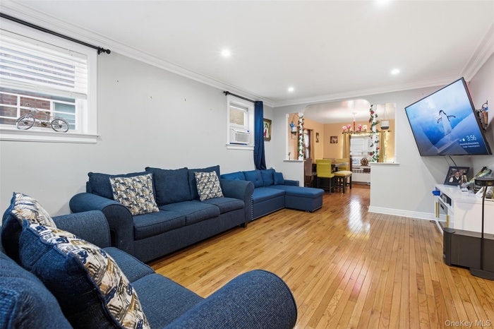Living room featuring light wood-type flooring, crown molding, recessed lighting, and a chandelier