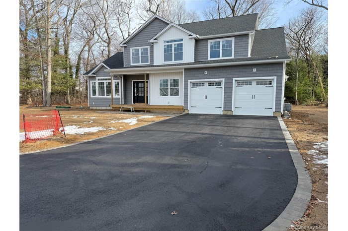 View of front of home featuring driveway, roof with shingles, covered porch, and an attached garage