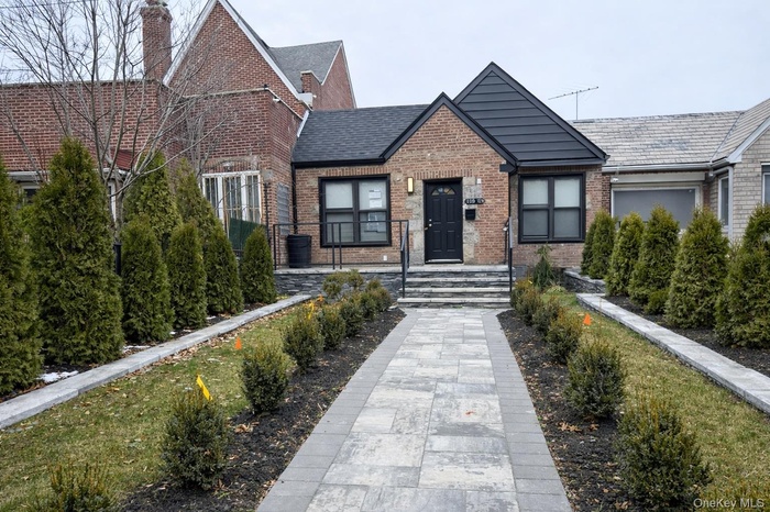 View of front of house featuring brick siding and a chimney