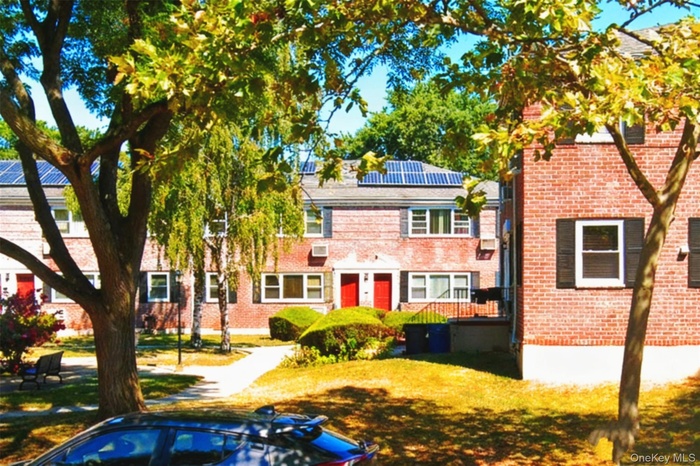 View of front of home with roof mounted solar panels, a front yard, and brick siding
