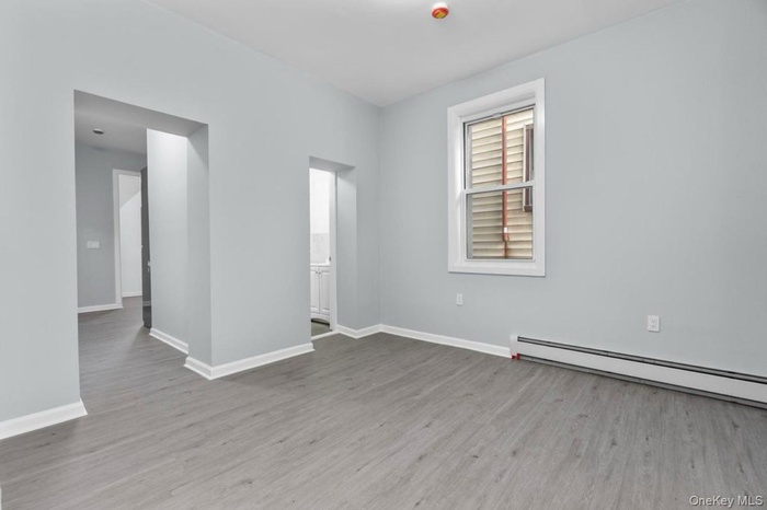 Empty room with light wood finished floors and baseboard heating