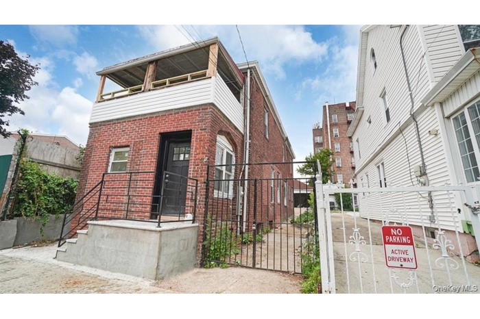 View of front property featuring brick siding, a balcony, and a gate
