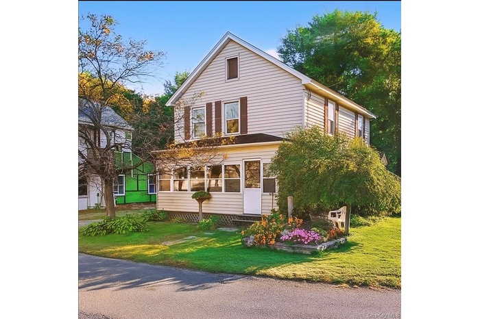 View of front of house with a sunroom and a front yard