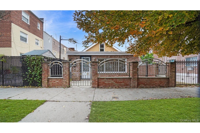 View of front of property with a fenced front yard, brick siding, and a gate