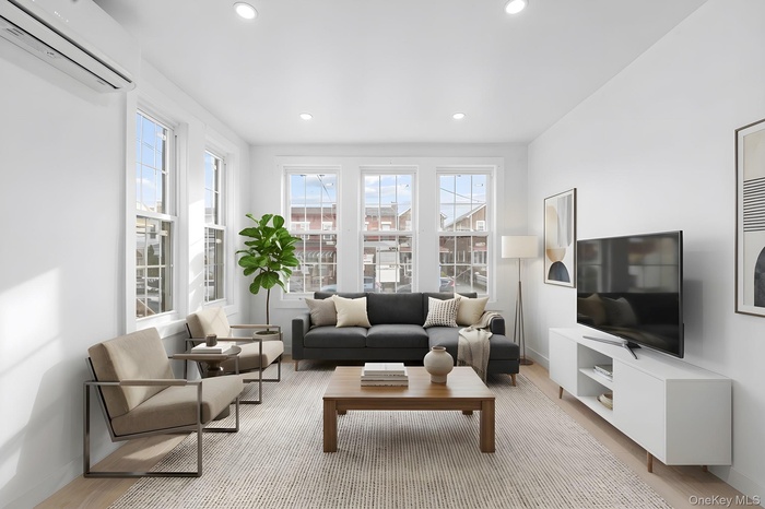 Living area with an AC wall unit, recessed lighting, and light wood-type flooring