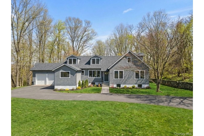 View of front facade featuring a front yard, asphalt driveway, and a garage
