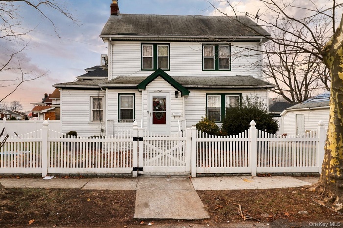 Traditional-style house with a gate, a chimney, and a fenced front yard
