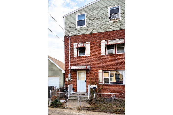 Traditional-style home featuring brick siding, a gate, a fenced front yard, and cooling unit