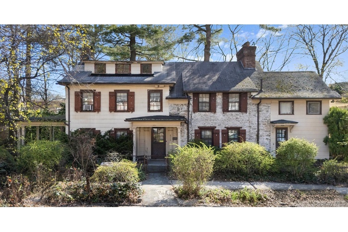 View of front of property with stone siding and a chimney