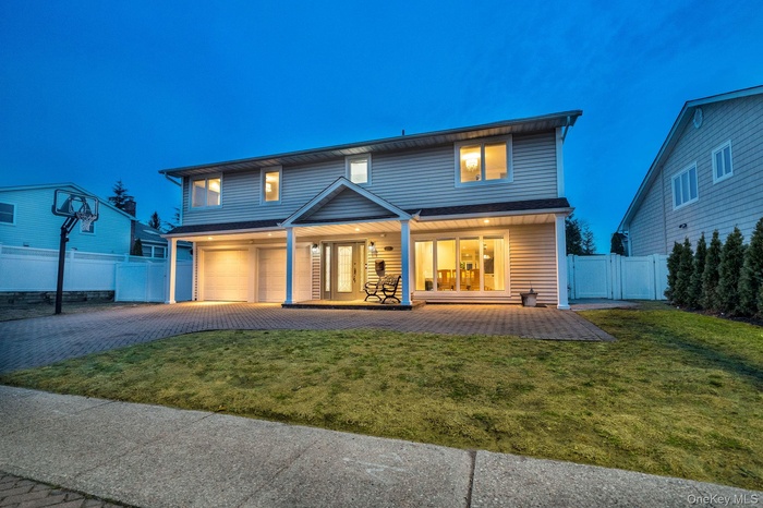 Rear view of property with decorative driveway, an attached garage, and a gate