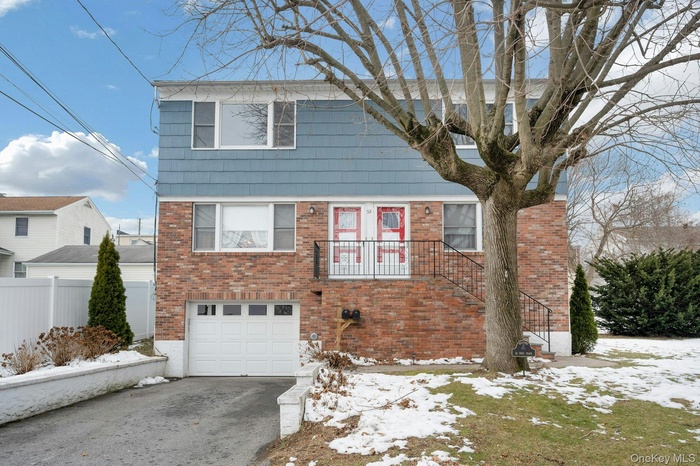 View of front facade with brick siding, a garage, and driveway
