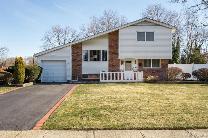 Tri-level home with asphalt driveway, brick siding, and covered porch