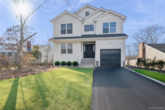 View of front facade with board and batten siding, asphalt driveway, and an attached garage