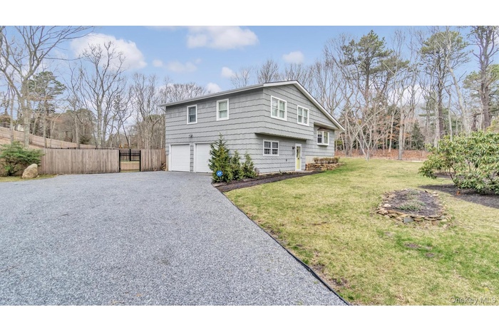 View of side of home with an attached garage, a lawn, aphalt driveway, and fence