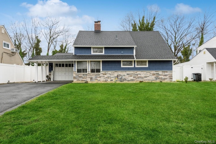 View of front of property with stone siding, a shingled roof, a chimney, and driveway