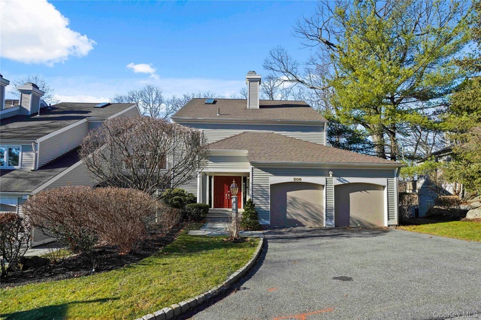 View of front of house with an attached garage, driveway, roof with shingles, and a front lawn