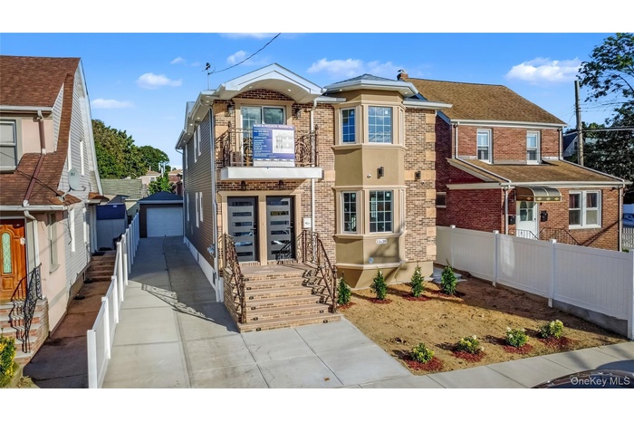 View of front of house featuring brick siding, an outbuilding, a detached garage, and a shingled roof