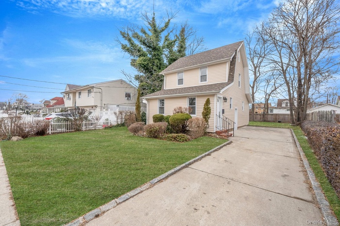 Traditional-style home featuring a shingled roof and driveway