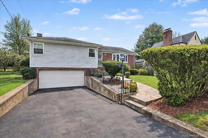 View of front of house featuring brick siding, driveway, a garage, and a front yard