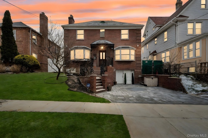View of front of home with brick siding, driveway, and a chimney