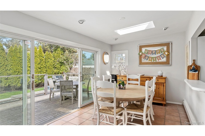 Dining space featuring baseboard heating, light tile patterned flooring, a skylight, and baseboards