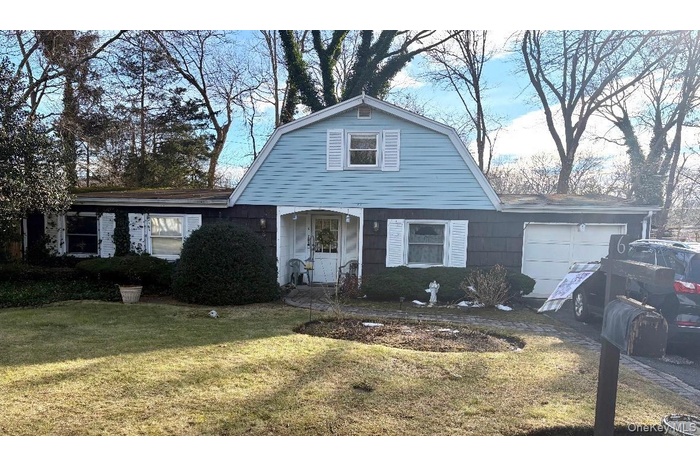 Colonial inspired home with a gambrel roof, a front yard, and an attached garage