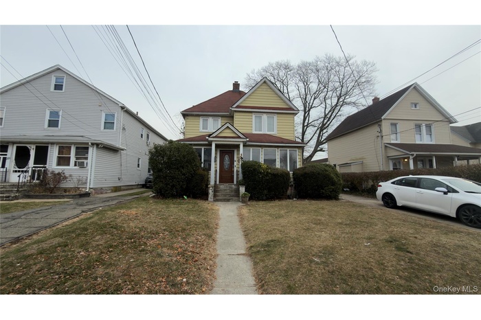 View of front of home with a chimney and a front yard