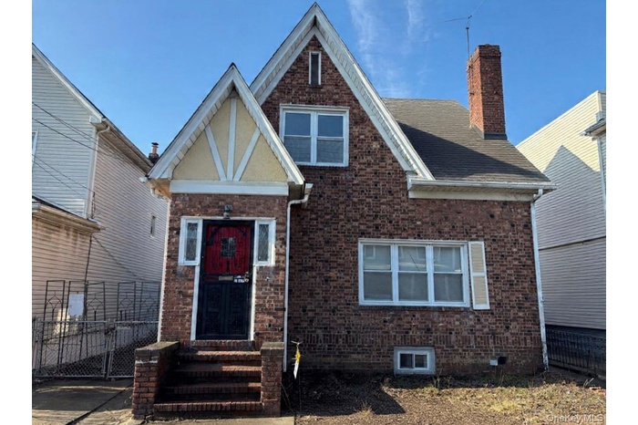 View of front facade featuring brick siding and a chimney