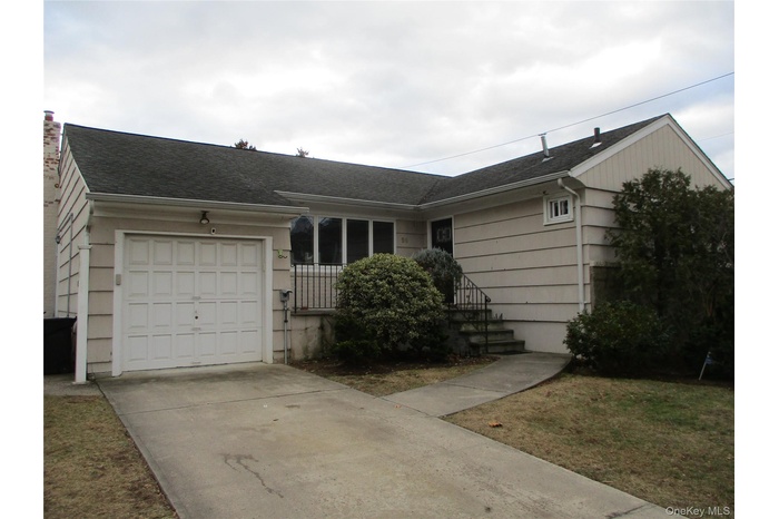 Single story home with a shingled roof, an attached garage, and driveway