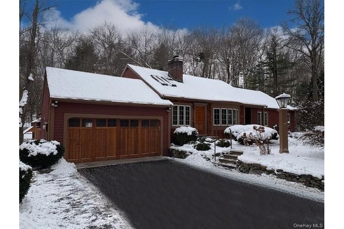 View of front facade with a chimney, a garage, and driveway