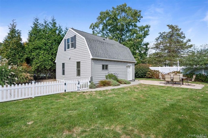View of side of property with a gambrel roof, a patio area, and a shingled roof