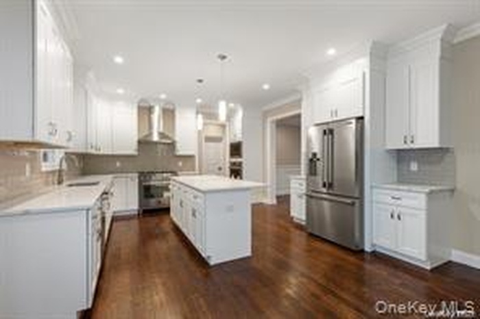 Kitchen with white cabinets, backsplash, light countertops, and recessed lighting