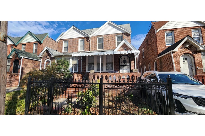View of front of property with a fenced front yard, a porch, and brick siding