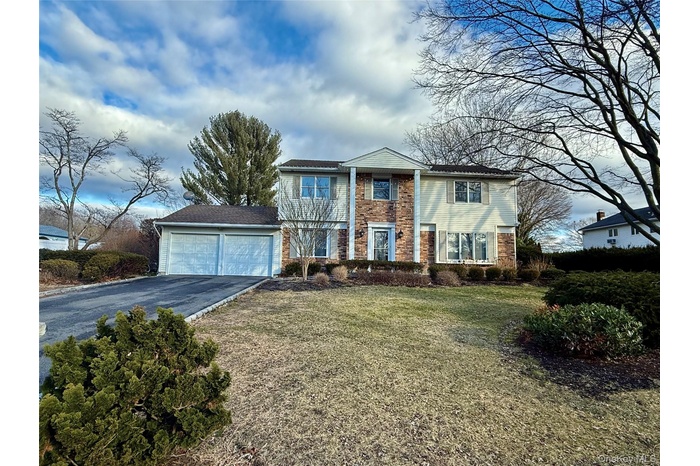 View of front of house with driveway, brick siding, and a front lawn
