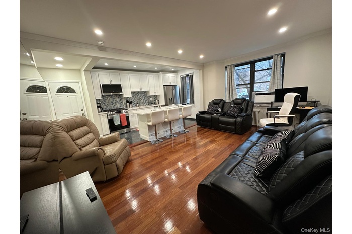Living area featuring dark wood-style flooring, ornamental molding, recessed lighting, and radiator