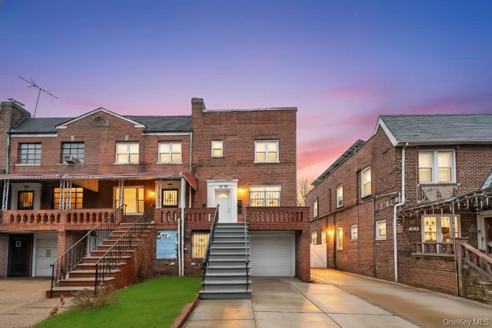 View of front of home featuring driveway, brick siding, a garage, and stairs