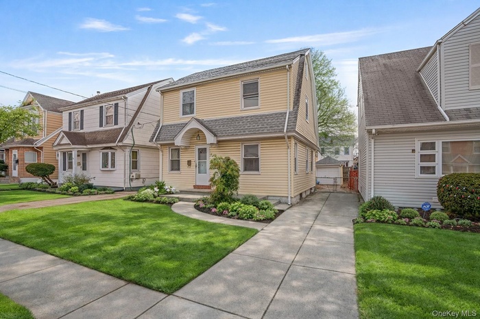 Dutch colonial with a front lawn, a shingled roof, and an outbuilding