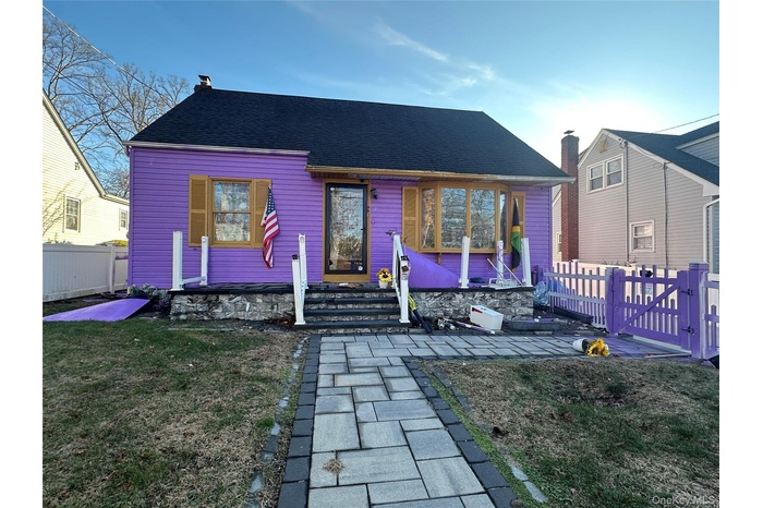 View of front facade featuring roof with shingles, a gate, and a chimney