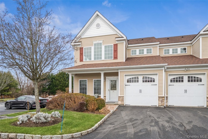View of front of property featuring asphalt driveway, a garage, a shingled roof, a front yard, and stone siding