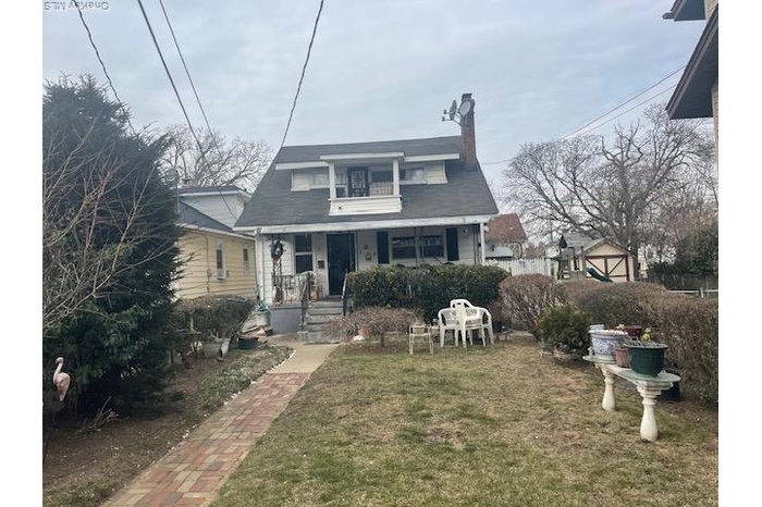 Bungalow-style home featuring a chimney, a front lawn, and a porch