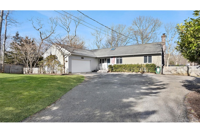 Ranch-style house featuring asphalt driveway, a garage, a chimney, and roof with shingles
