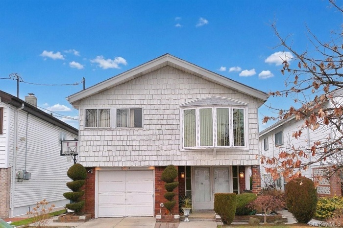 View of front of property with brick siding, an attached garage, and driveway