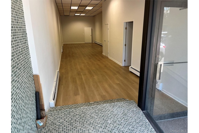 Hallway with a drop ceiling, a baseboard heating unit, wood finished floors, and a heating unit