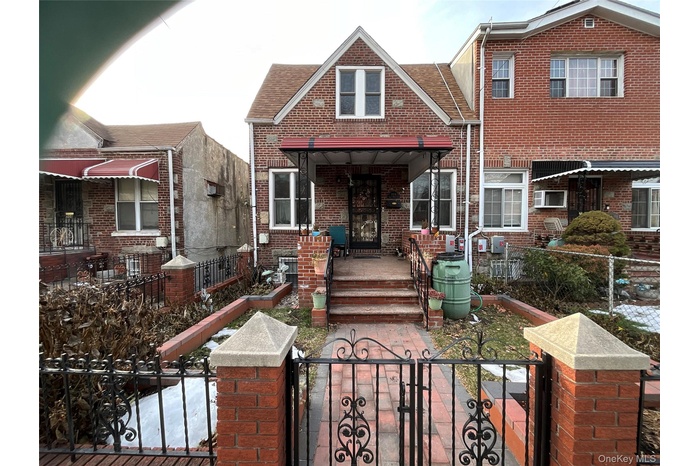 View of front facade featuring a gate, brick siding, and a fenced front yard