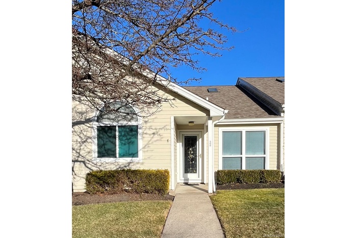 Property entrance with a lawn and roof with shingles