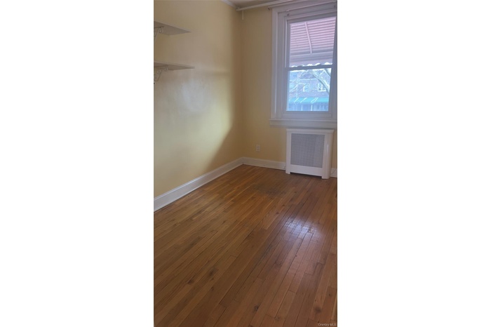 Empty room with radiator and dark wood-style flooring